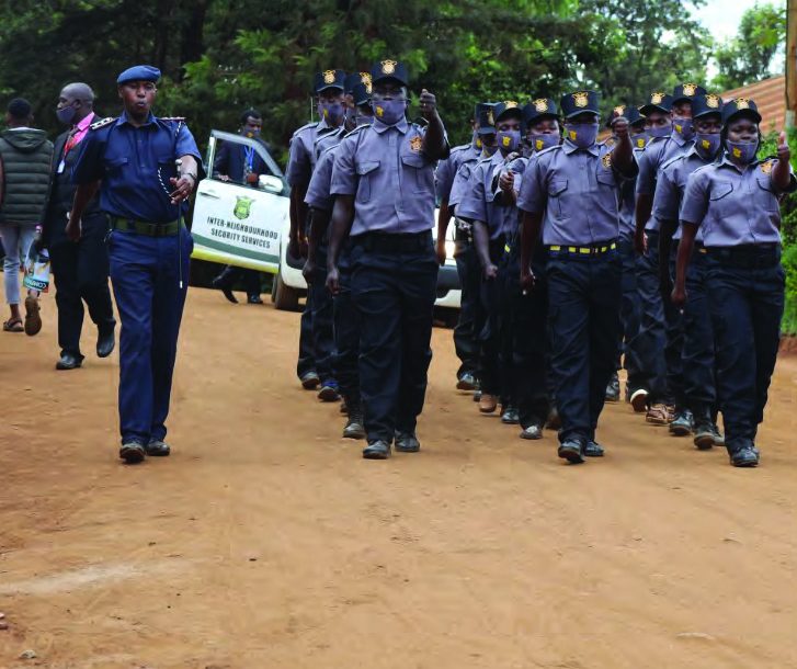 INS guards marching in formation beside a company patrol vehicle